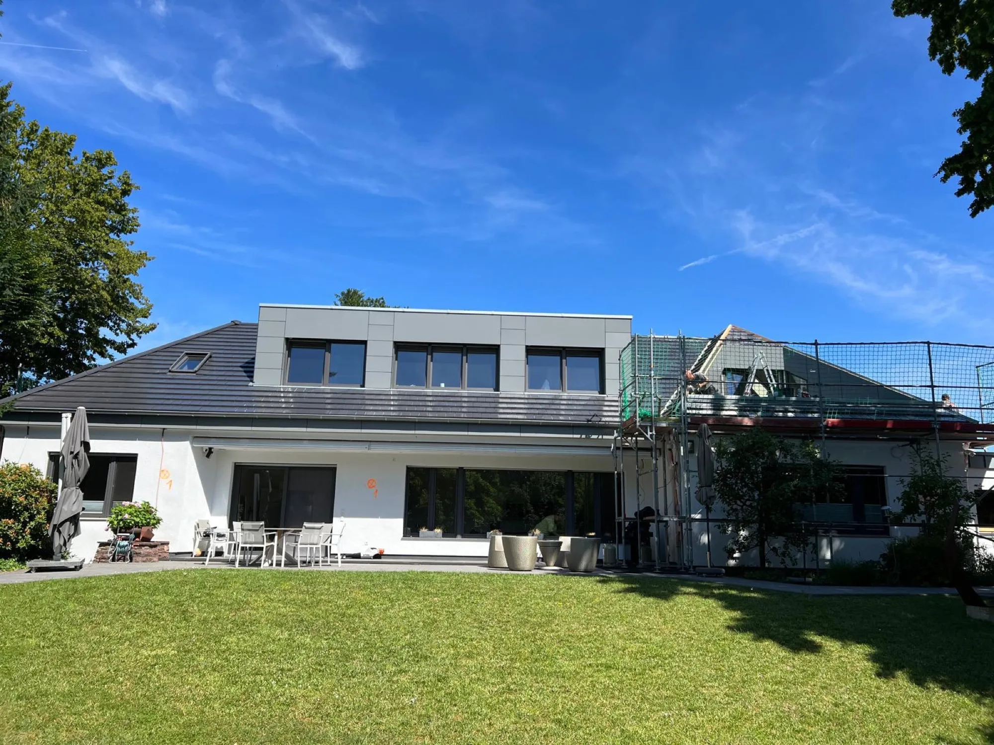 Aufstockung mit Zinkverkleidung im Bau – eingerüstet mit Schutznetz, Hombach & Schäfer