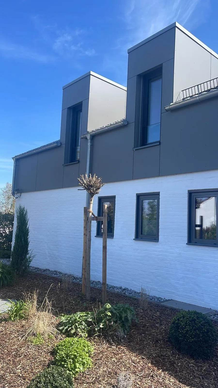 Obergeschoss in dunkler Metallbekleidung über weiß geschlämmtem Klinker