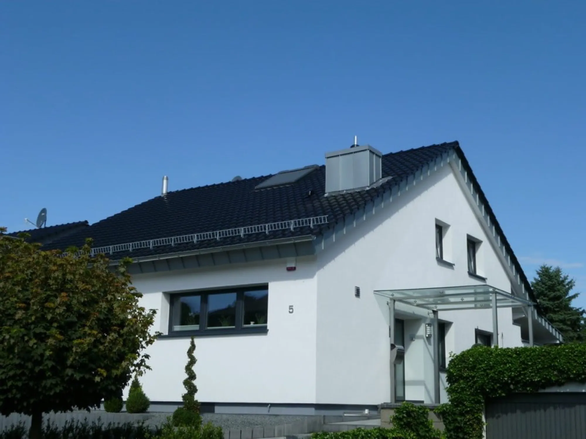 Neu eingedecktes Steildach mit anthrazitem Ziegel und Schneefanggitter im Kreis Düren