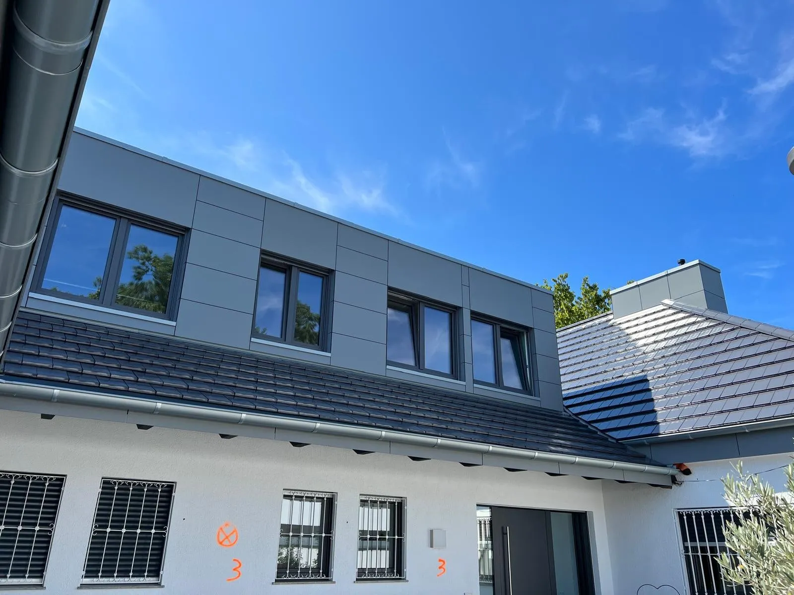 Aufstockung mit Fensterband über der neuen Ziegeldeckung
