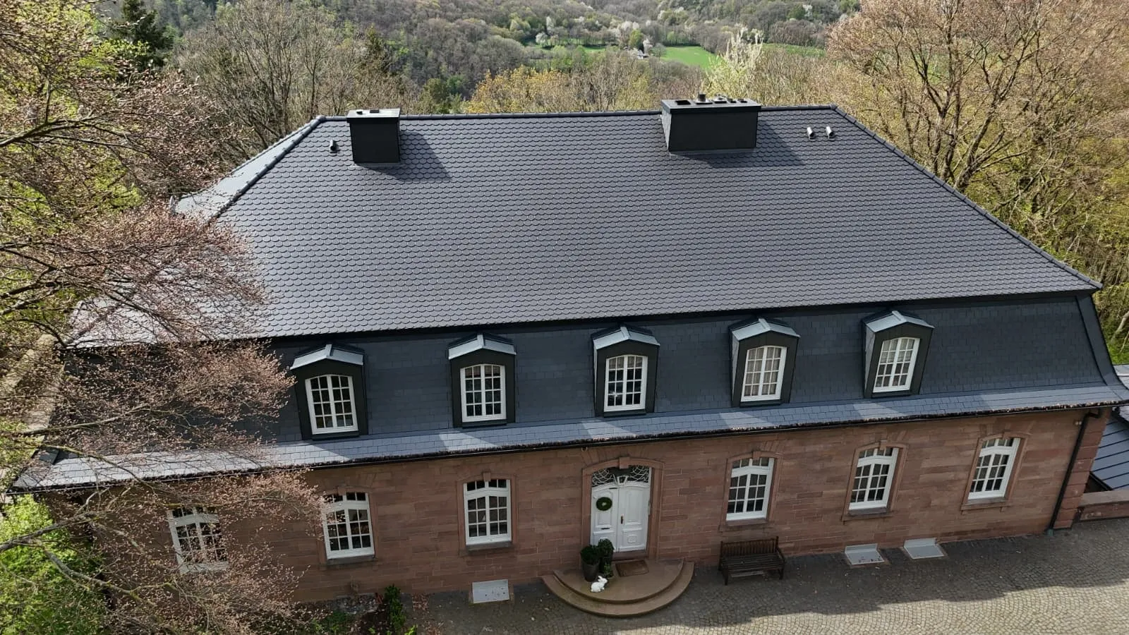 Herrenhaus mit neu eingedecktem Mansarddach und Fledermausgauben, Aufnahme aus der Luft